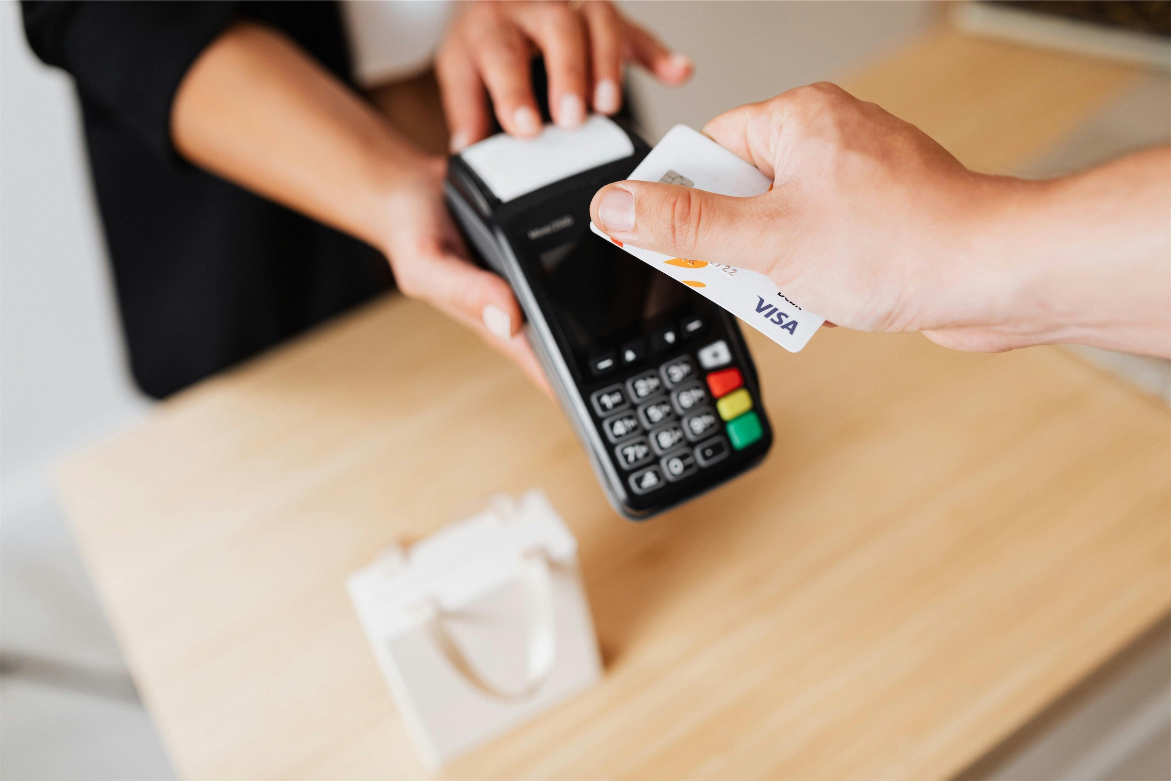 A customer tapping a card on a payment terminal held across a counter.